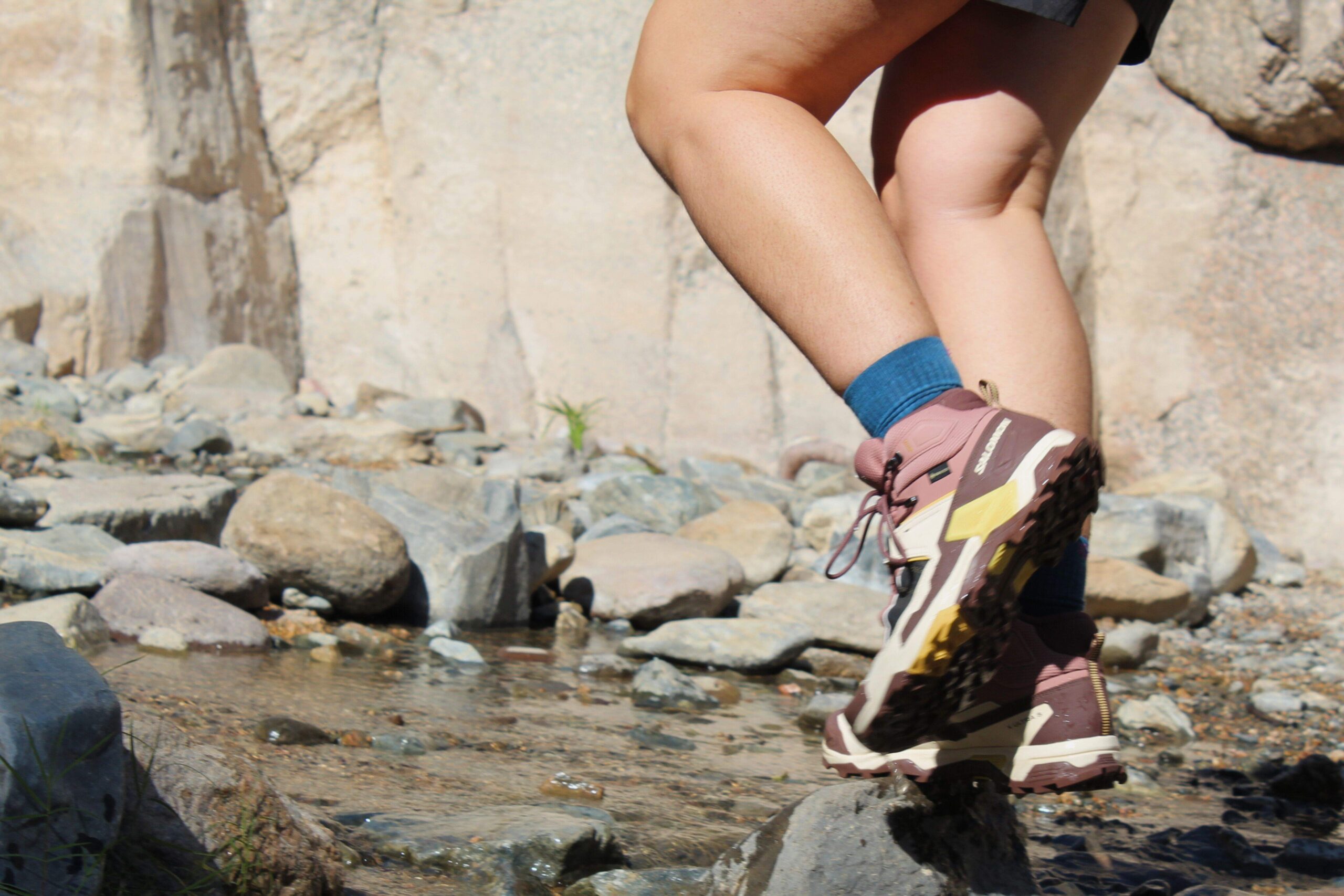 Hiker walking through a shallow stream wearing the Salomon X Ultra 5 GTX Women's Hiking Boots
