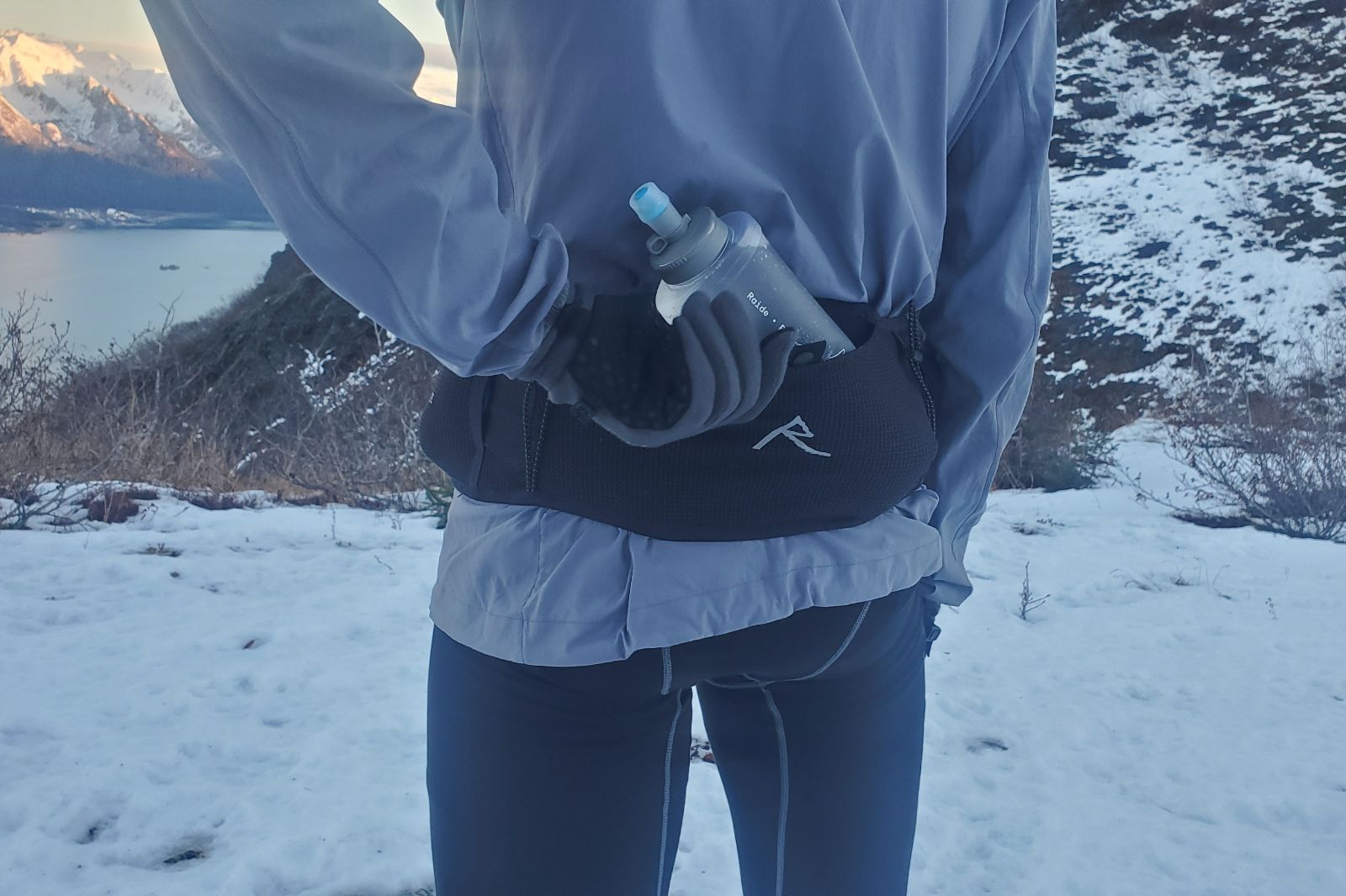A closeup of a gloved hand grabbing a water bottle.