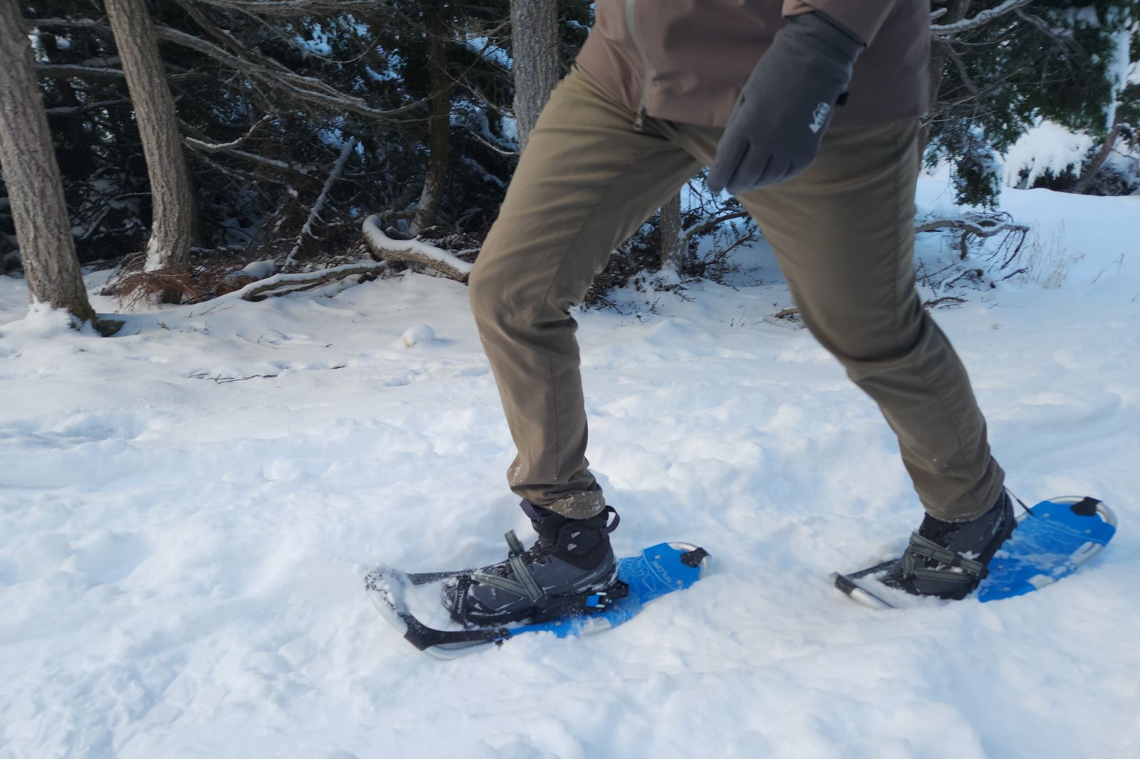 A mam walks up a snowy hill through the forest.