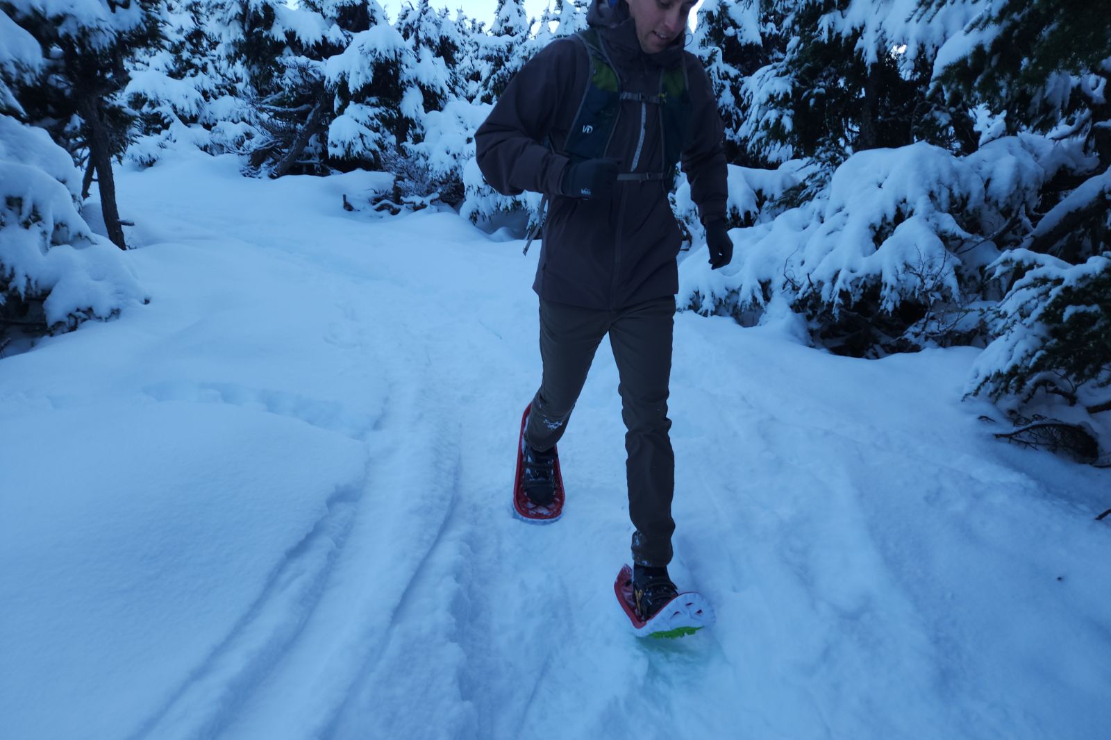 A man runs downhill while wearing snowshoes.