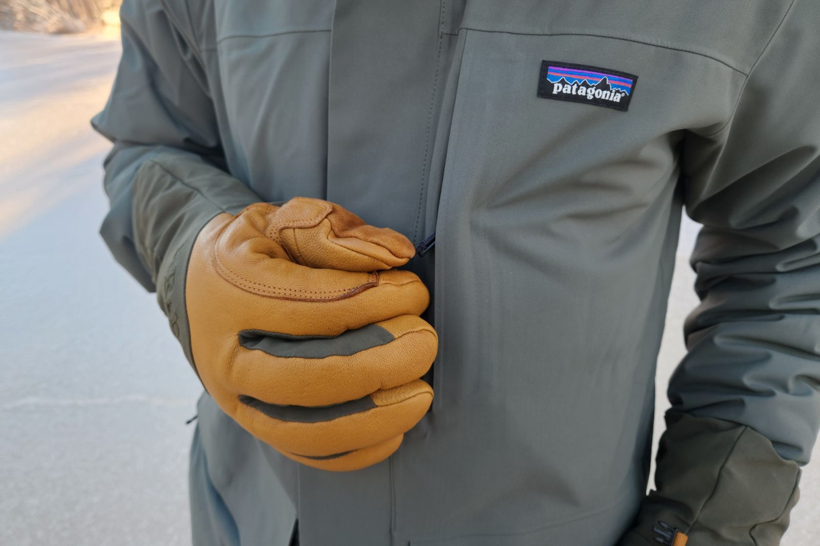A gloved hand grasping a jacket zipper.