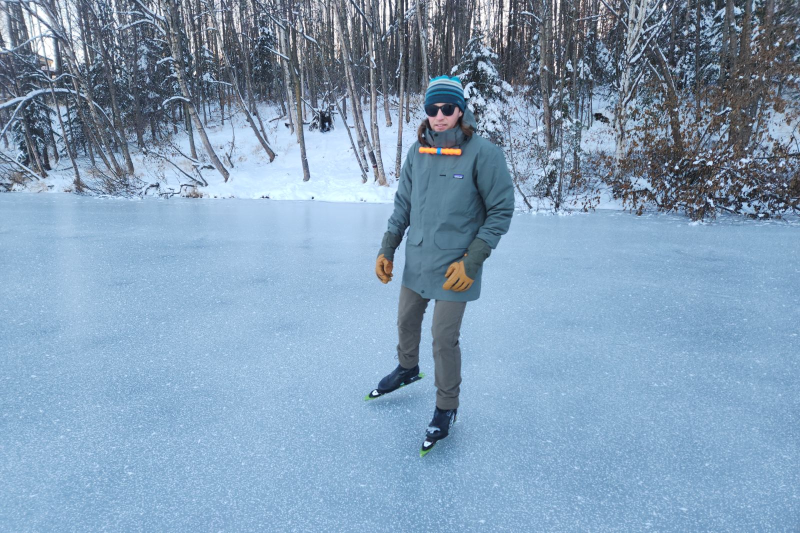 A man iceskating wearing a green jacket.