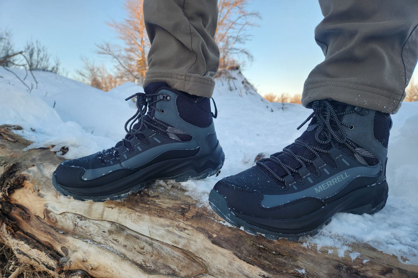 A closeup of winter boots standing on a snow-covered log.