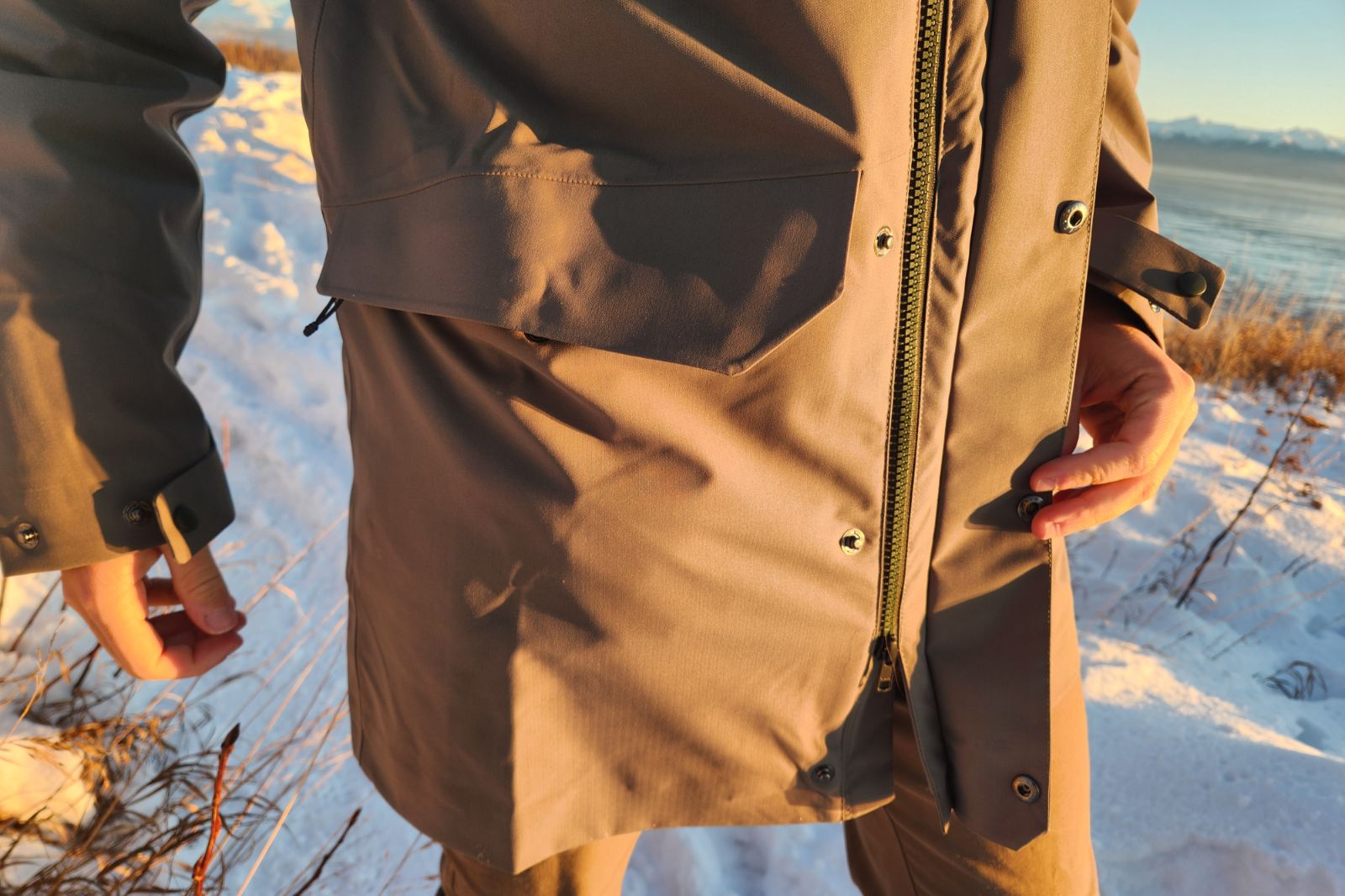 A closeup of the front zipper of a green jacket.