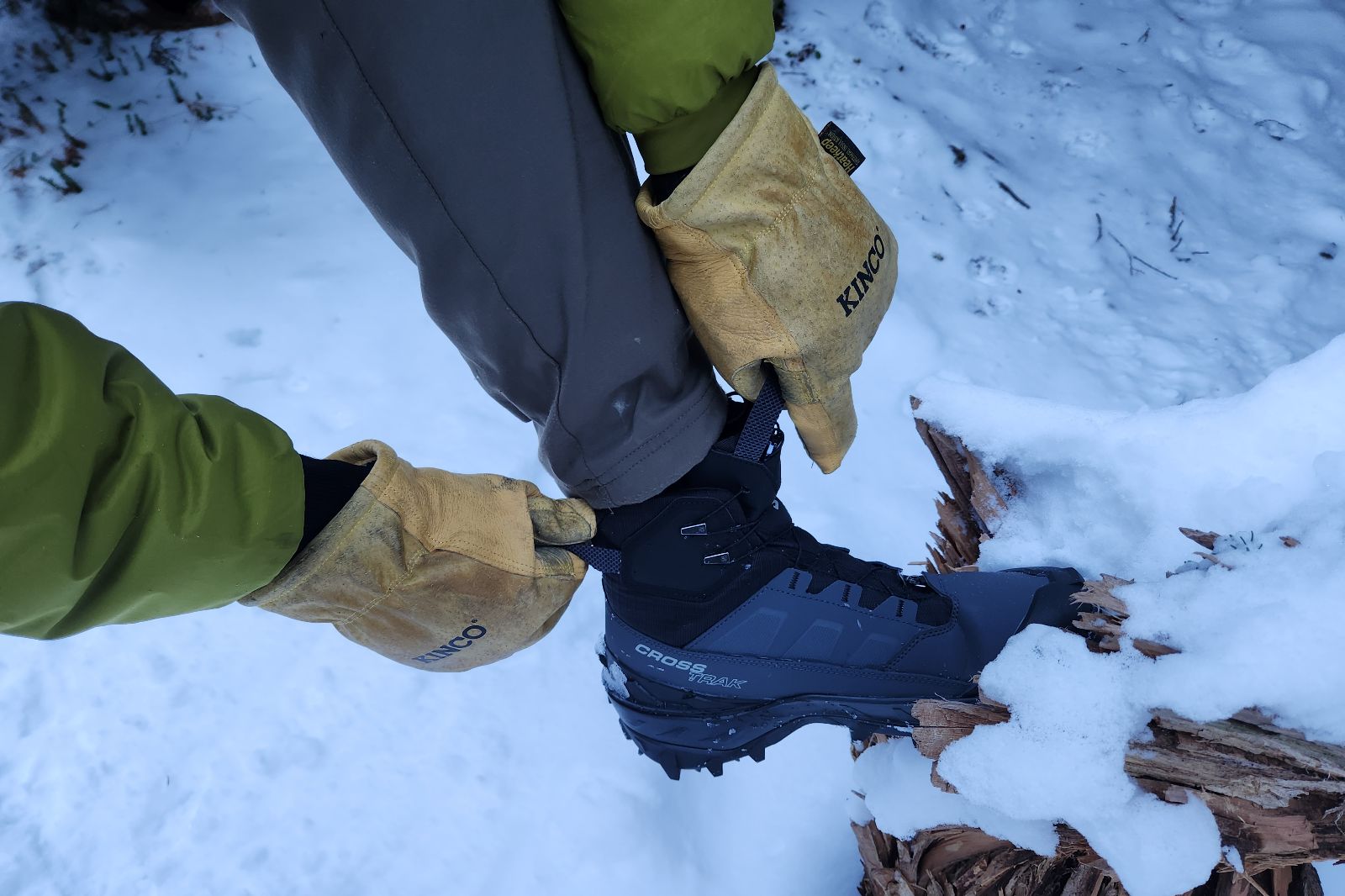 A closeup of gloves being worn while adjusting winter boots.