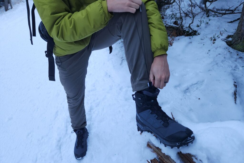 A man tightens the laces of his winter boots.