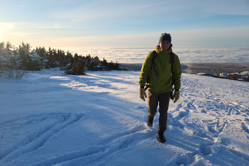 A man hikes above a cloud-filled valley in thr winter.