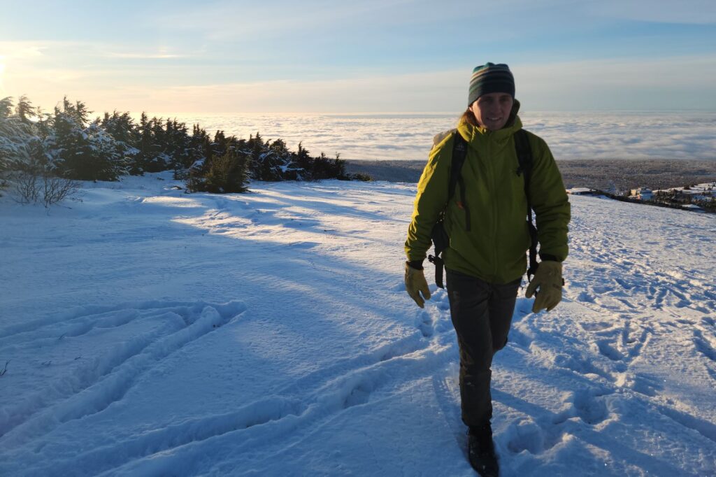 A man hikes above a cloudy view in the winter.