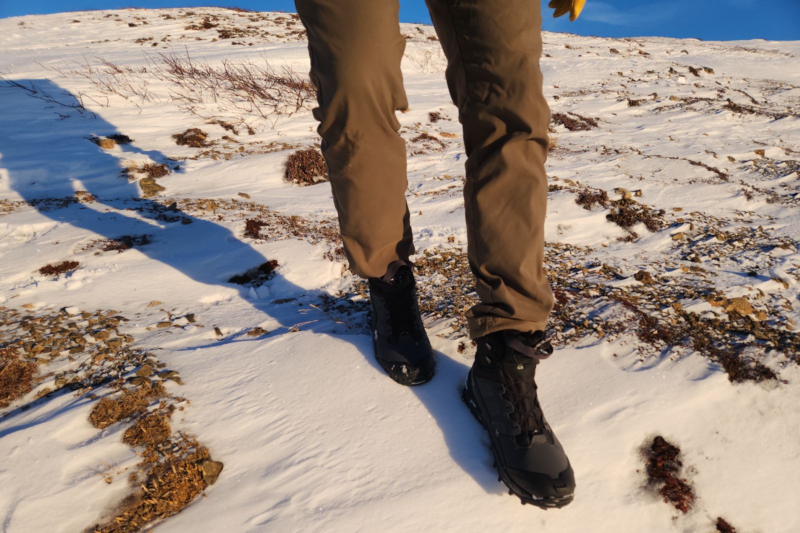 A pair of legs hiking while wearing winter boots in the tundra.