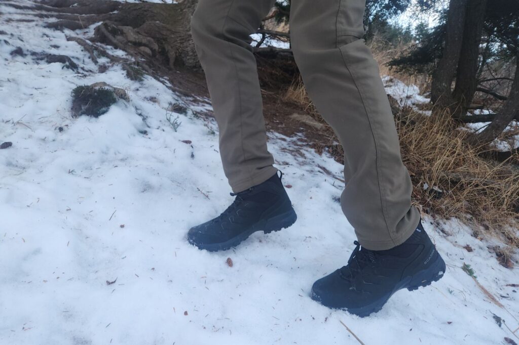 A pair of boots kicking steps in steep snow.