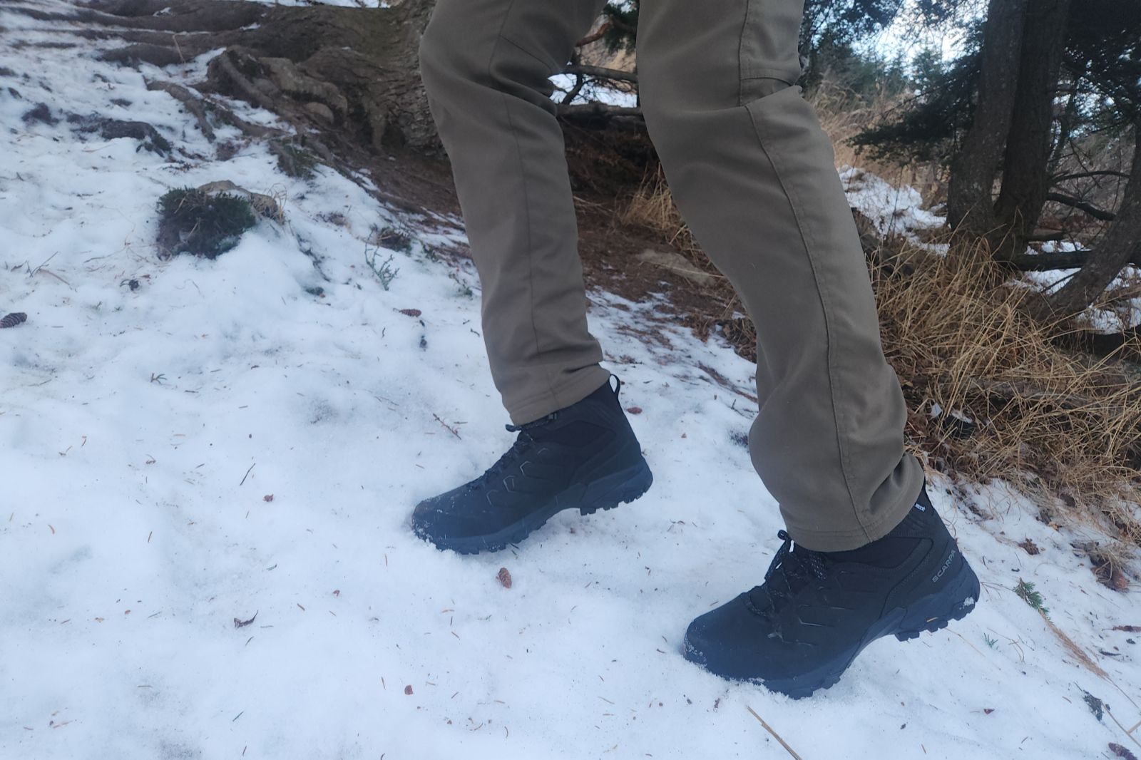 A pair of boots kicking steps in steep snow.