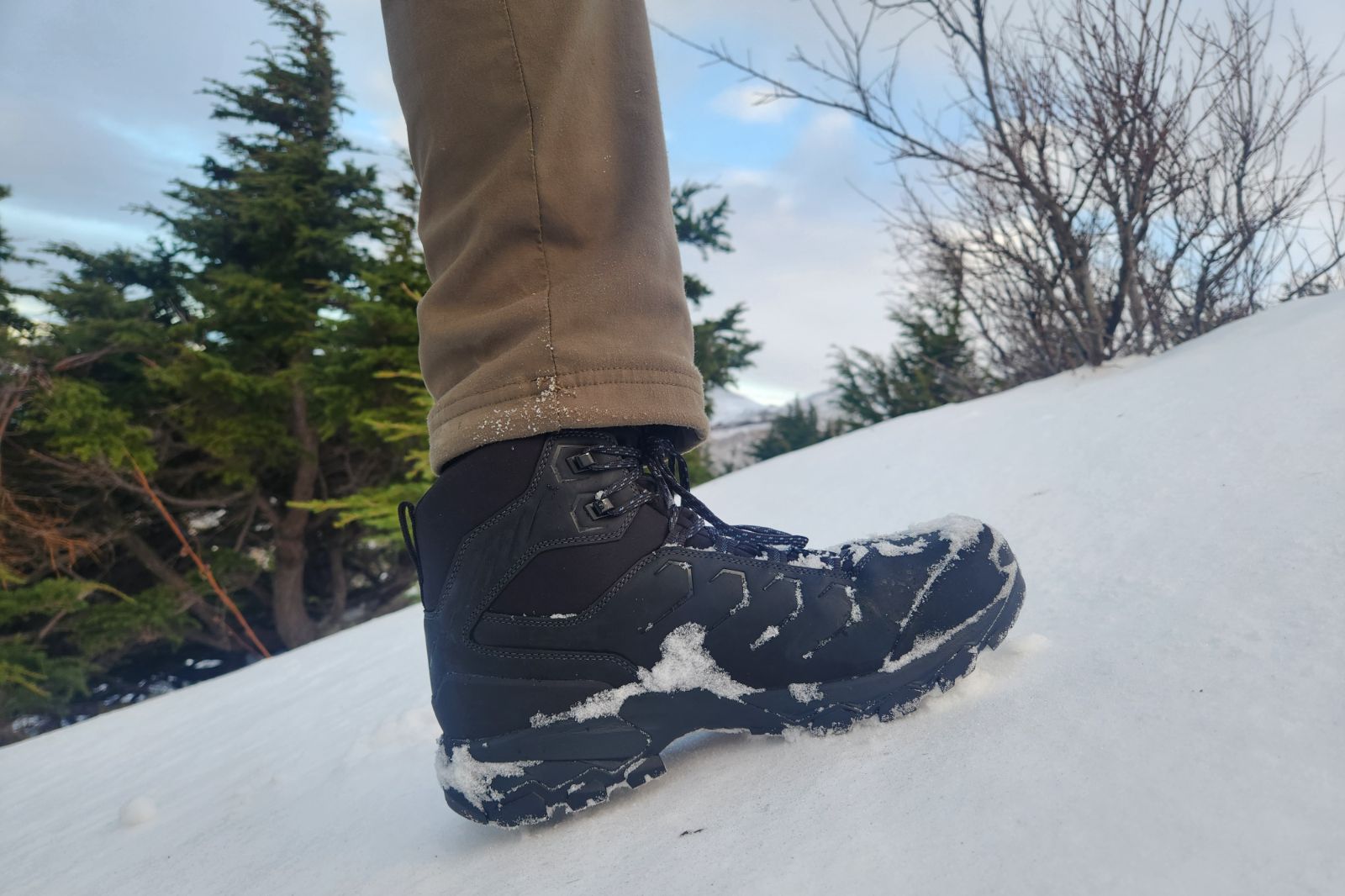 A pair of winter boots taking a step in deep snow.