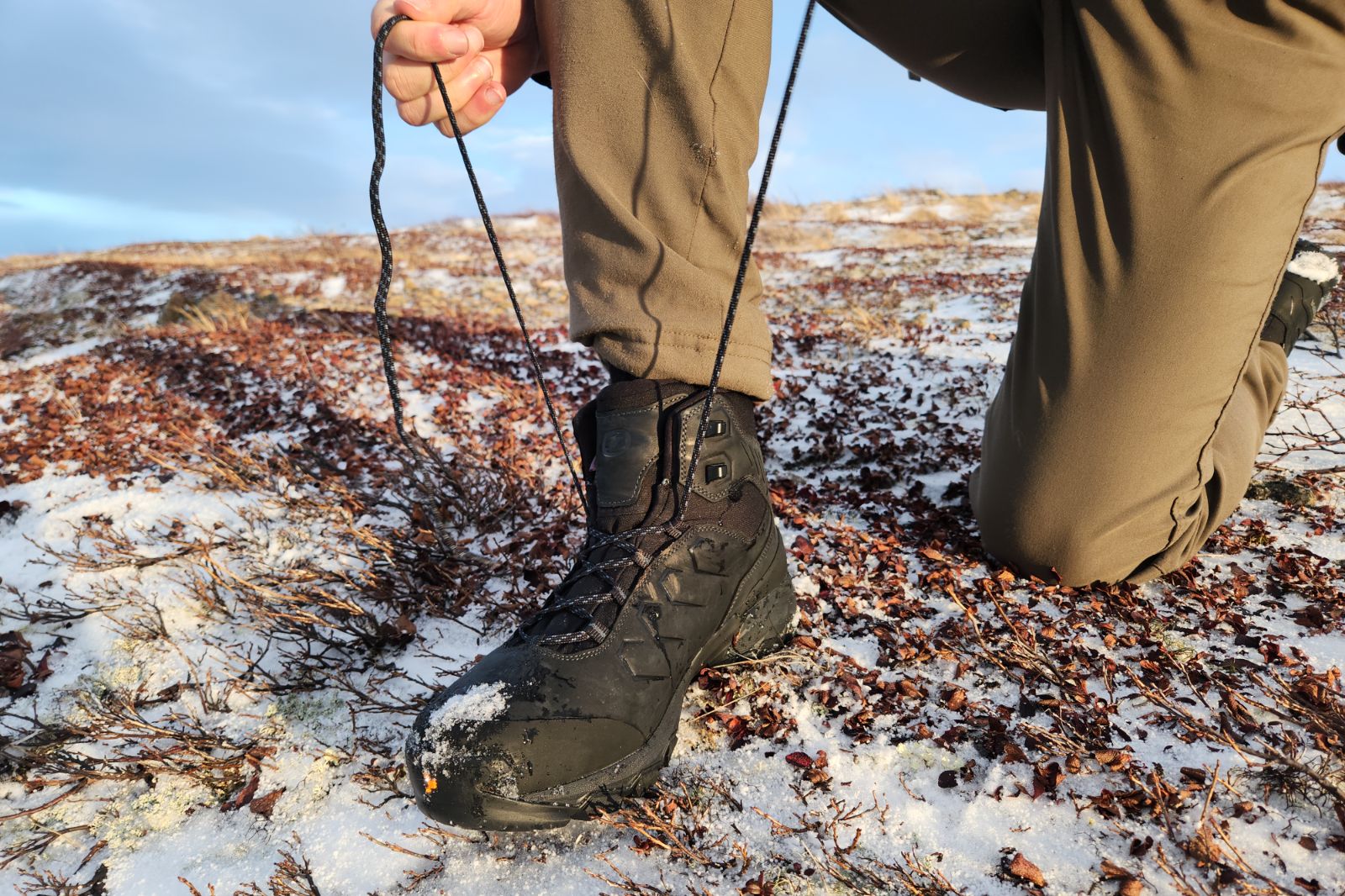 A man tightens the laces on his winter boots.