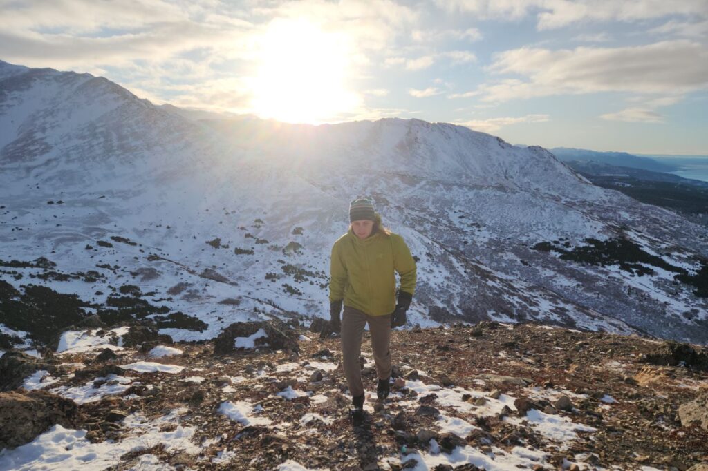 A man hikes in rocky alpine at sunset.