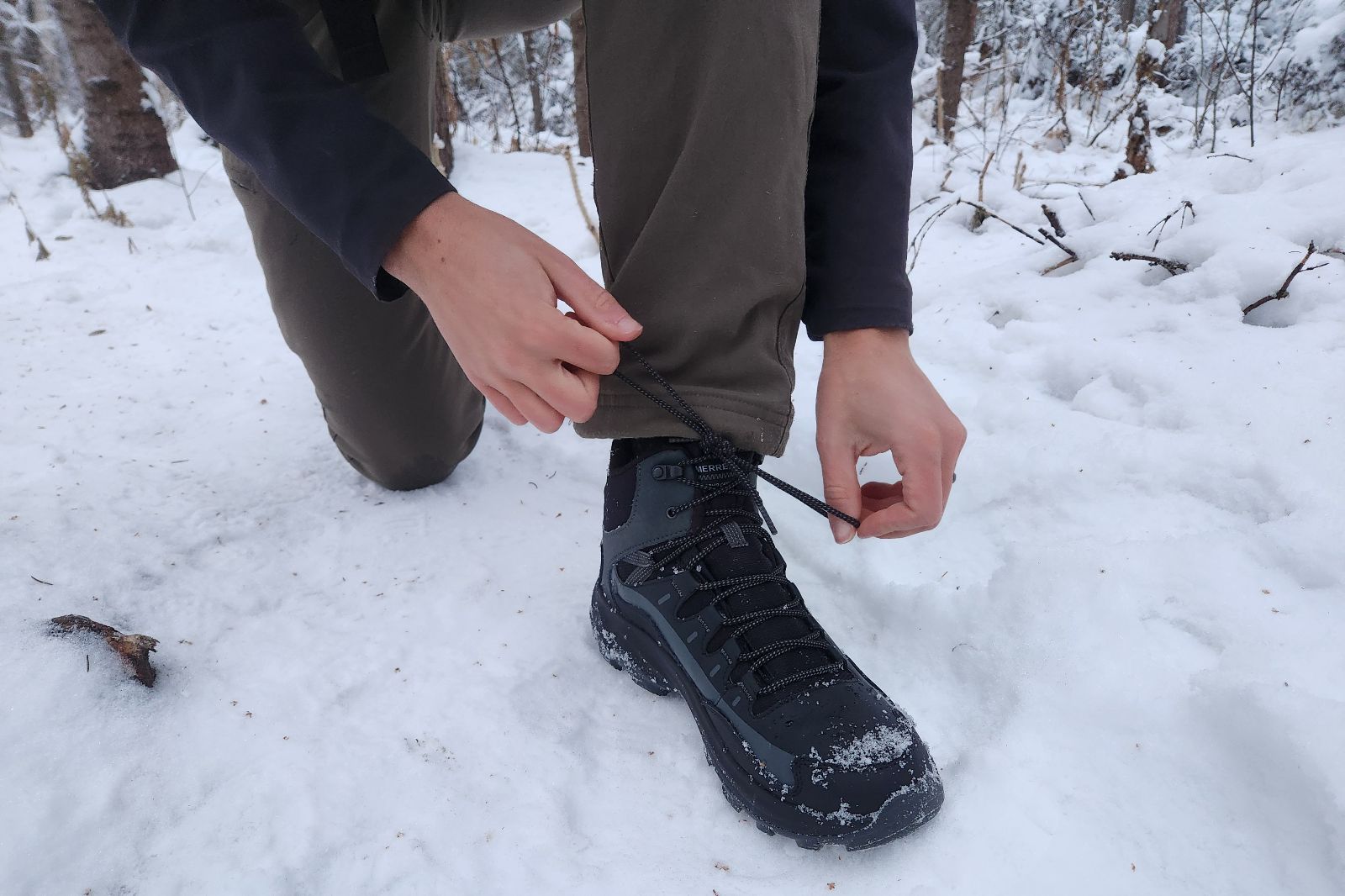 A man tightens the laces of his winter boots.