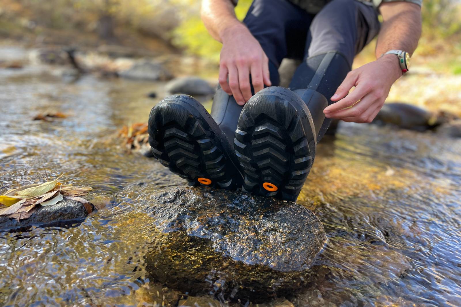 Showing off the tread of the Bogs Classic Seamless Tall Boots while sitting in a stream.