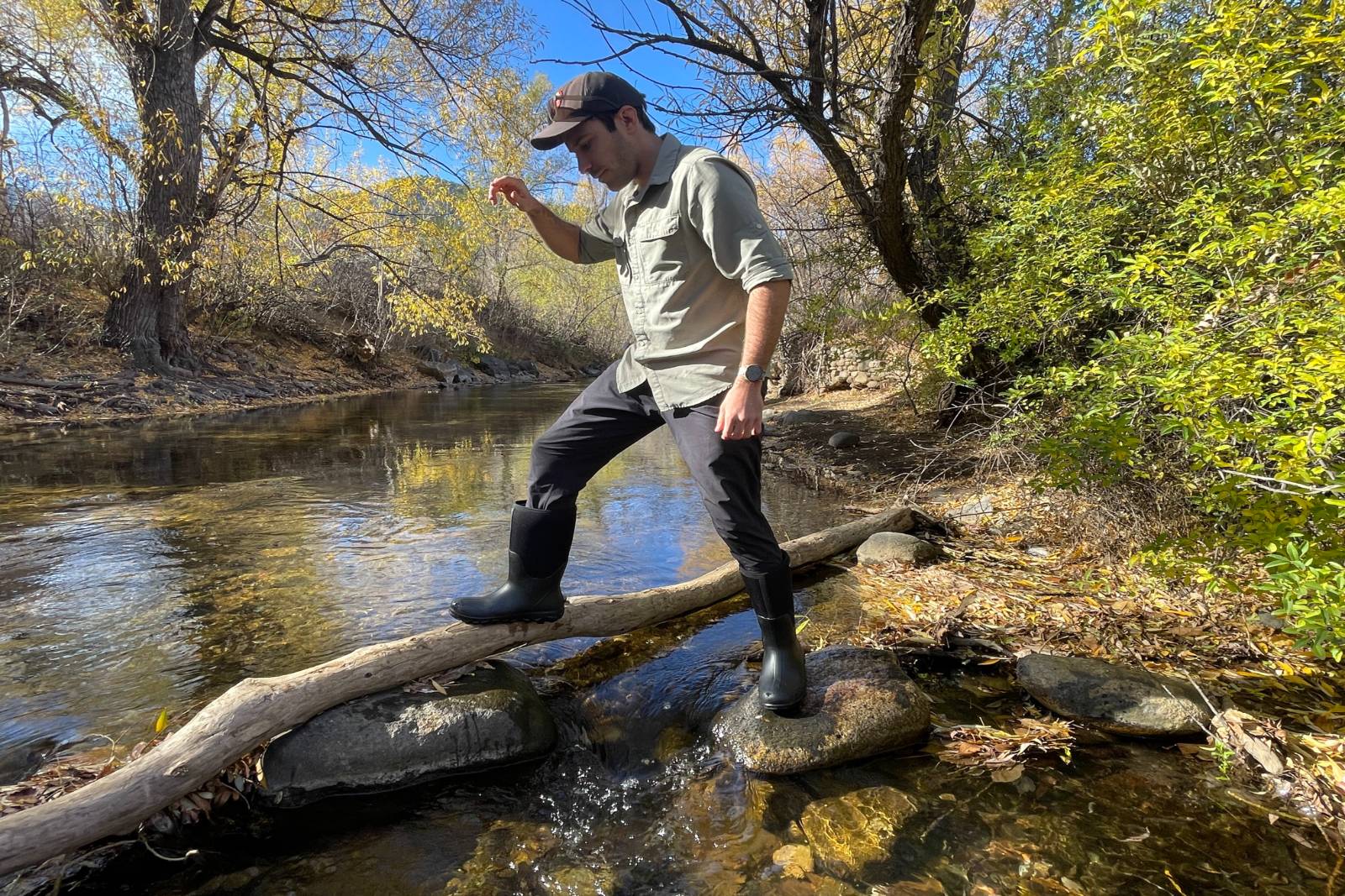Stepping from stone to log above a stream in the Bogs Classic Seamless Tall Boots.