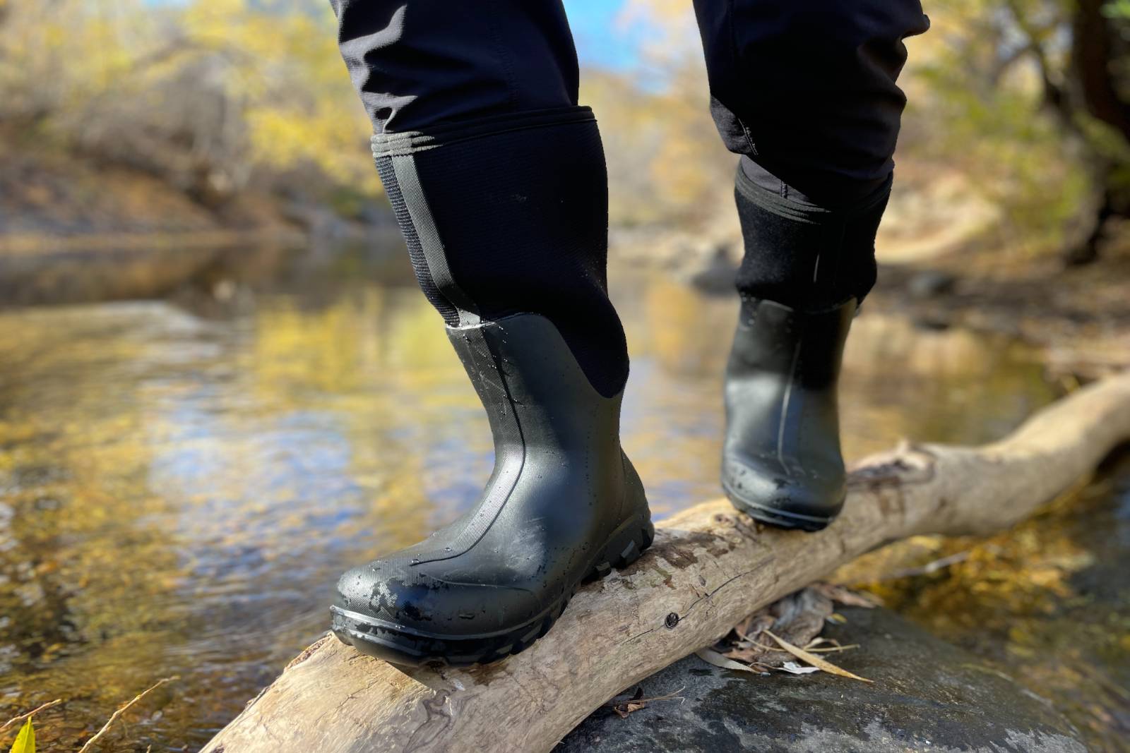 Balancing and walking along a log above a stream in the Bogs Classic Seamless Tall Boots.