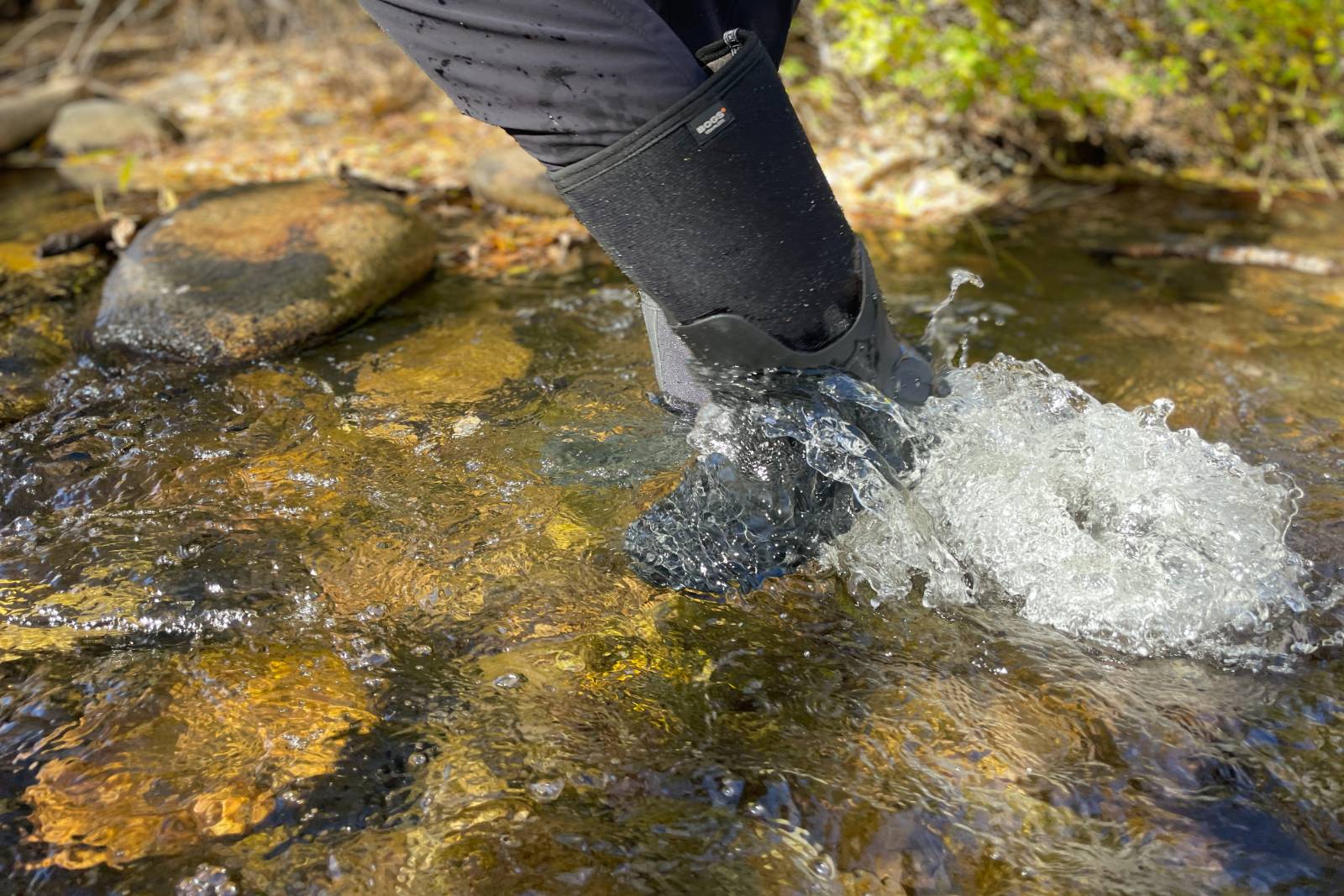 Action shot stepping through water in a stream with the Bogs Classic Seamless Tall Boots.