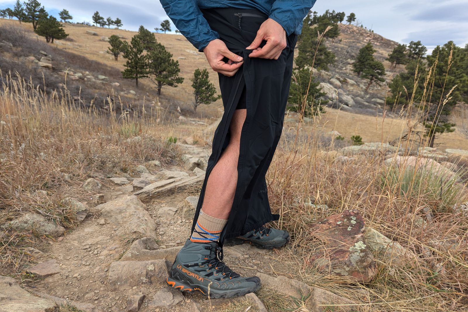 Demonstrating the full length side zips of the Mountain Hardware Stretch Ozonic rain pants.