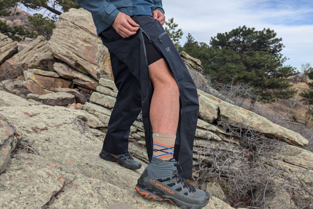 Demonstrating the full length side zips on the Arc'teryx Beta Pants.