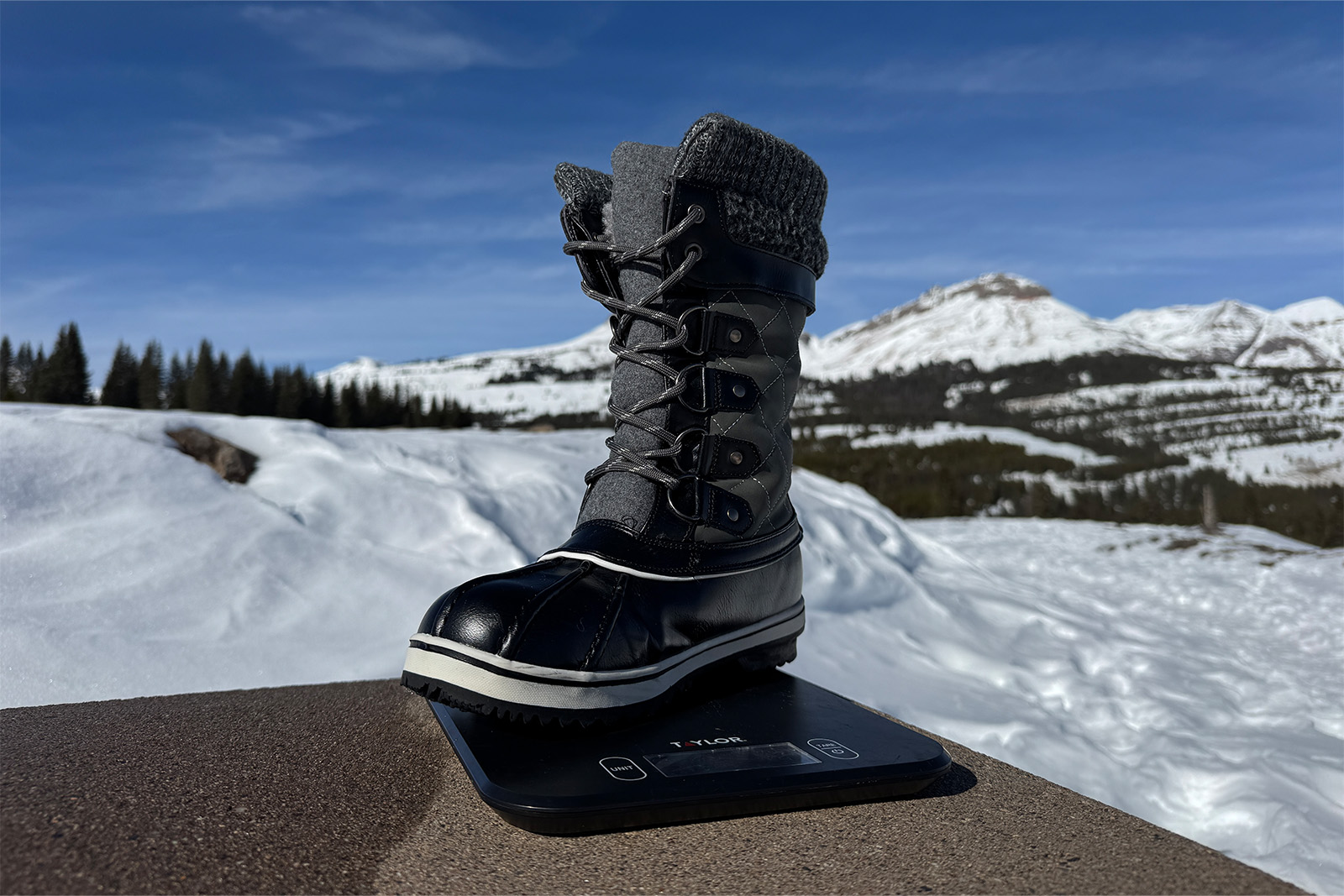 A Dream Pairs boot sits on a kitchen scale. There are mountains in the background.