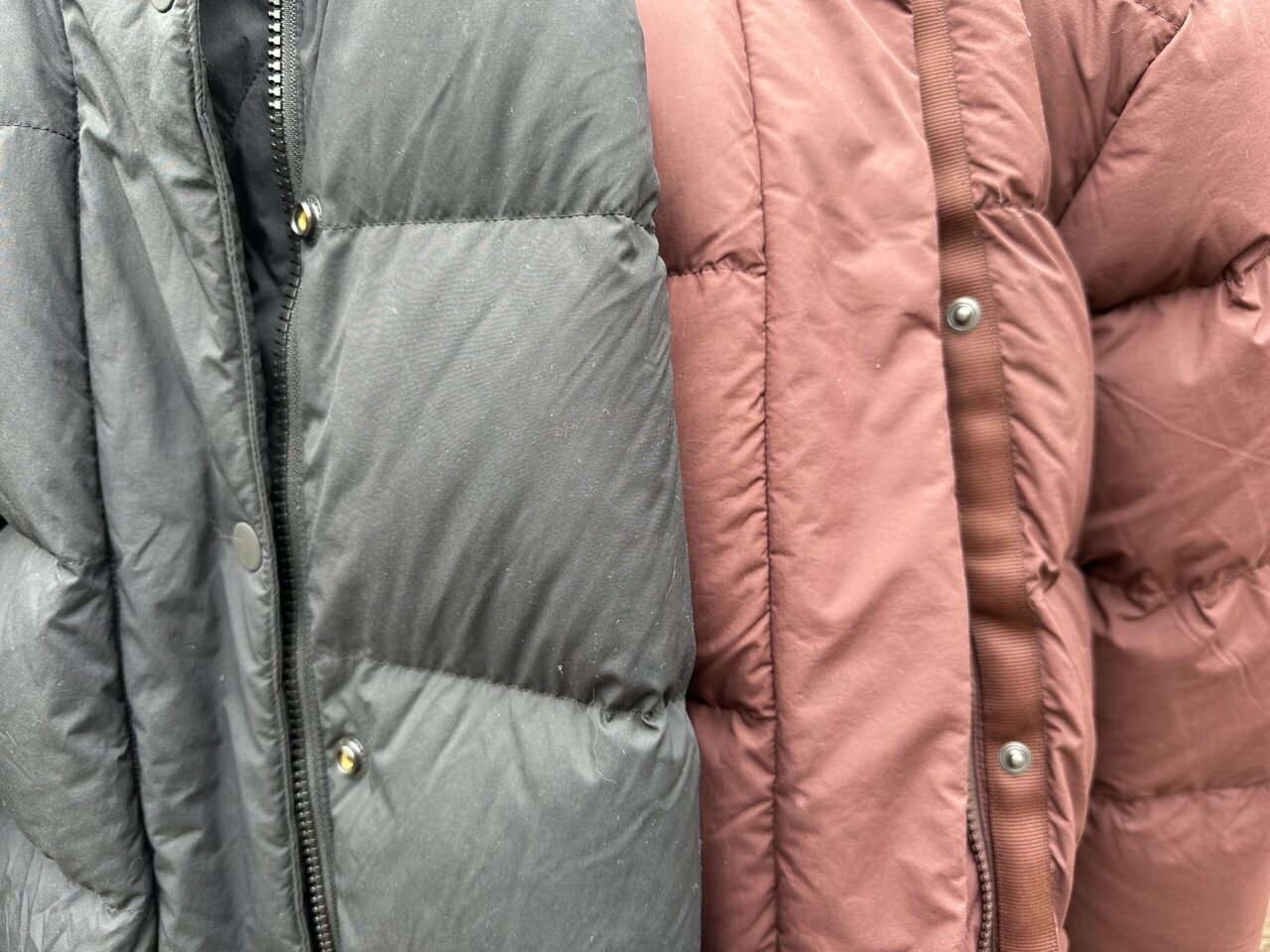 close up of two winter parkas font button and storm flaps