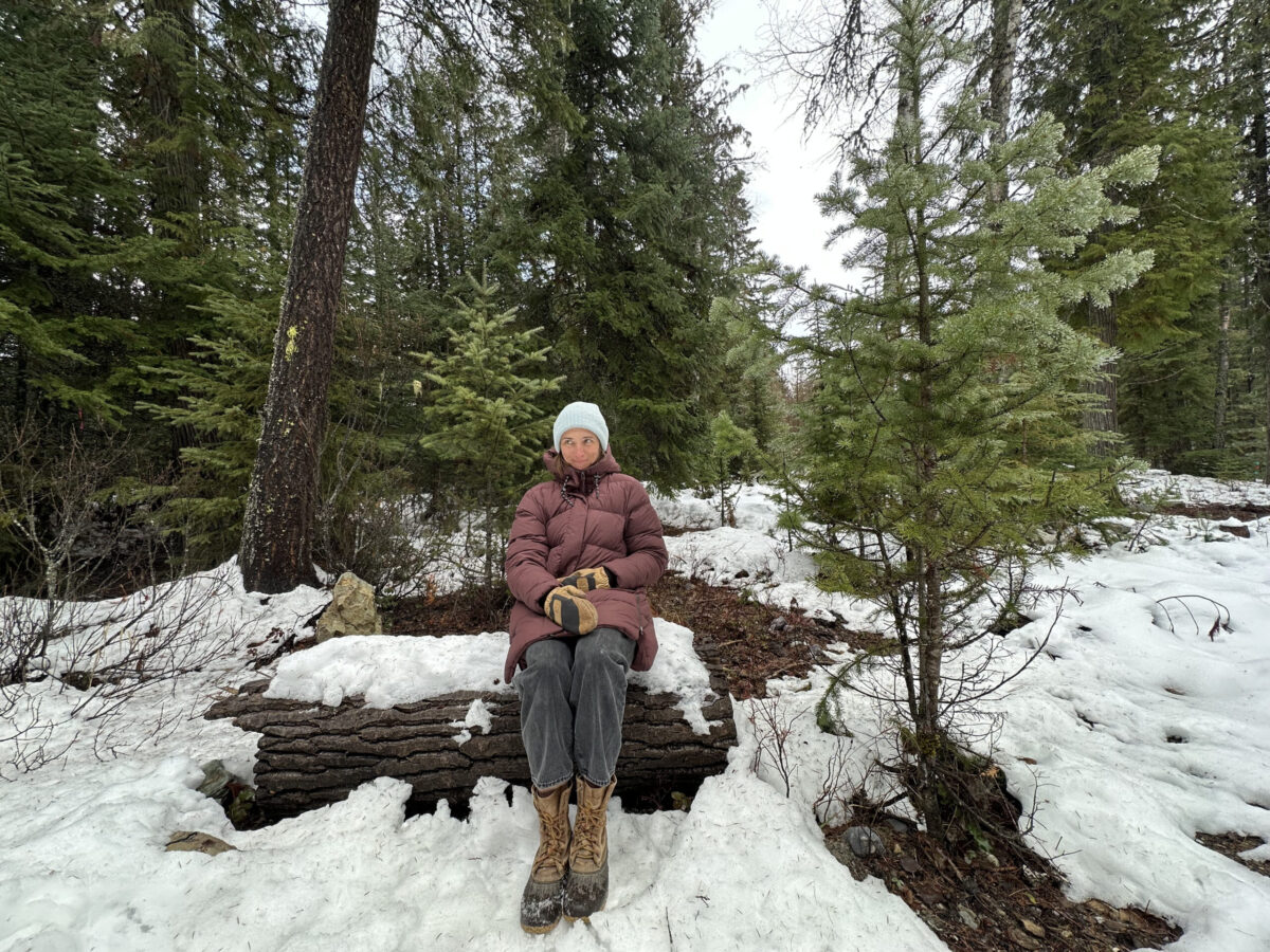 women sitting on a log in a snowy forest