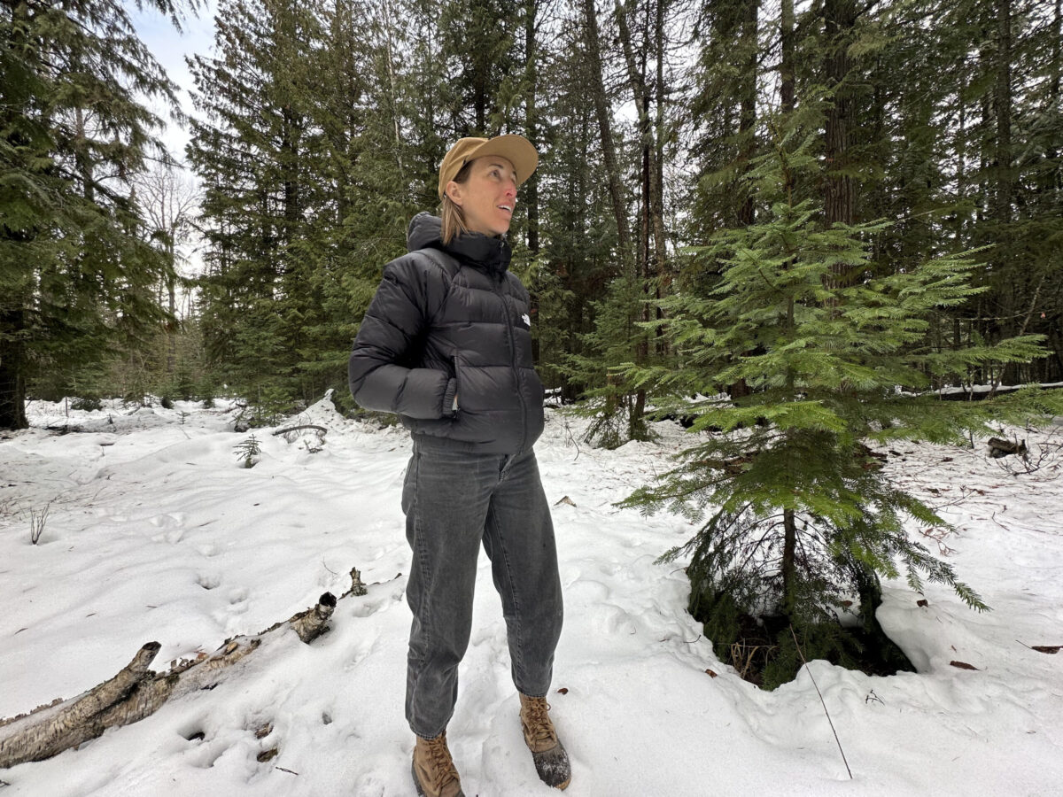 women in a winter forest in a black down puffy hoodie