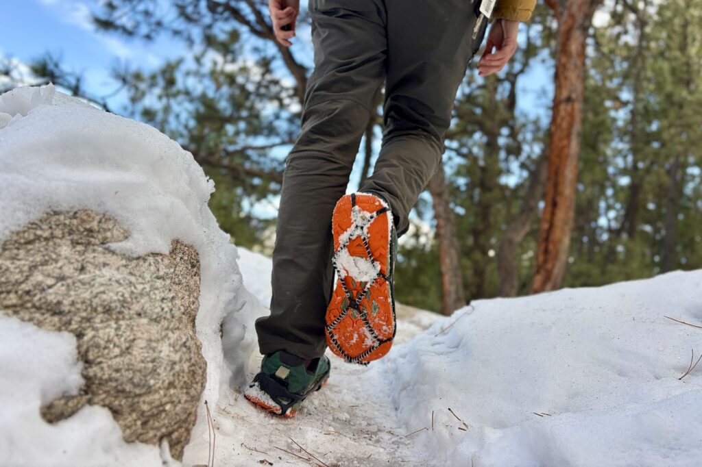 a hiker walks away from the camera showing the bottom of one shoe with a traction device attached