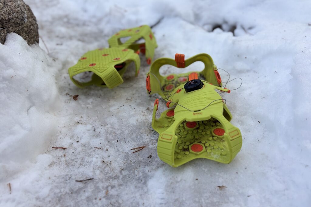 a pair of green BOA ice cleats sitting on snow