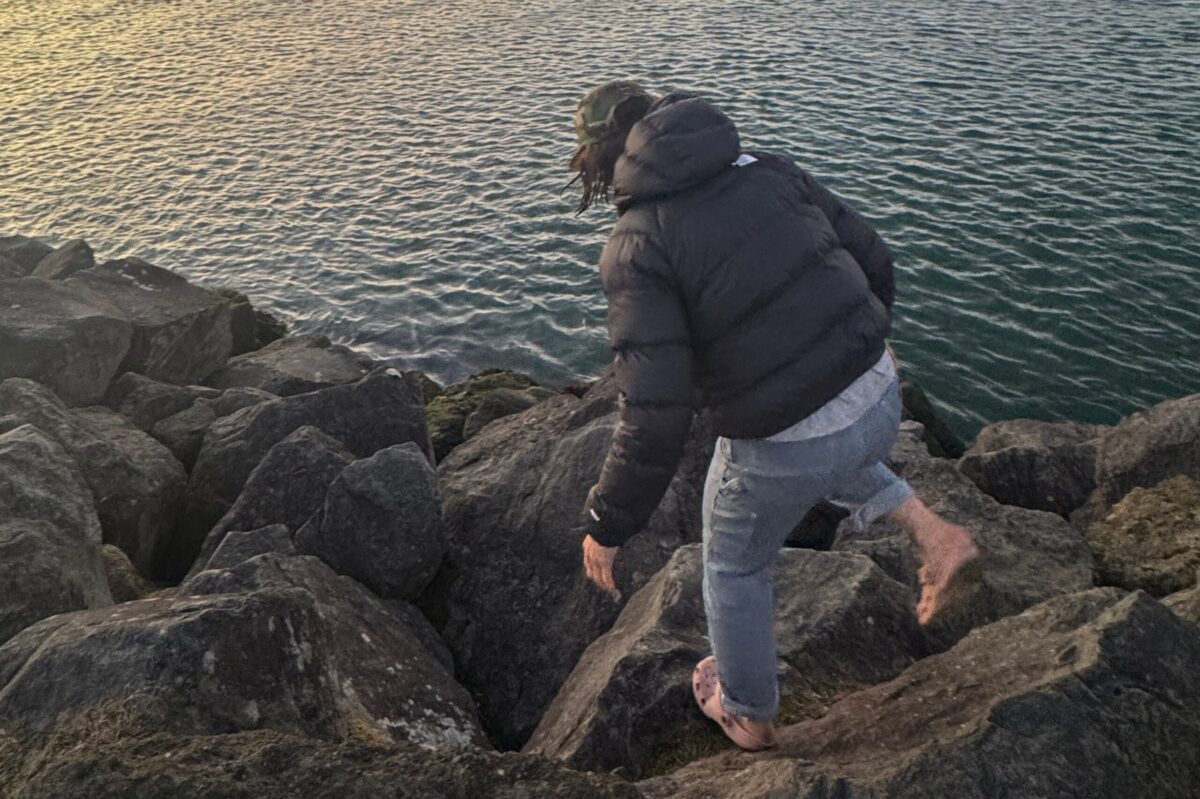 women walking on rocks with water in the background
