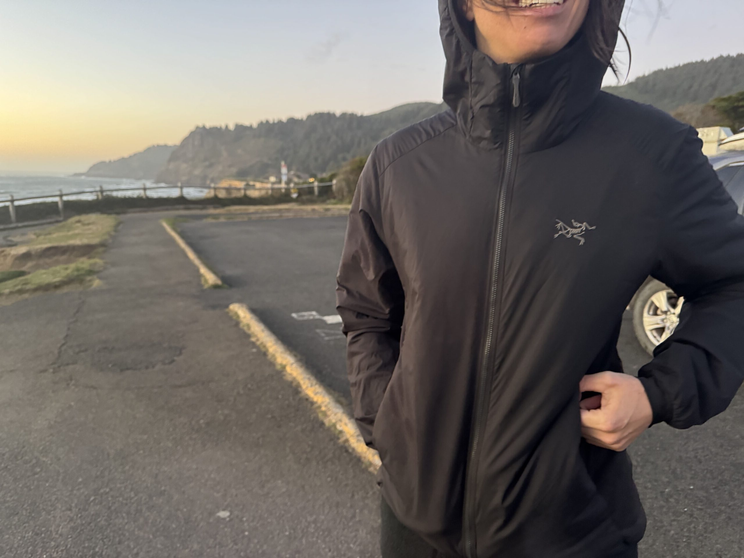 woman wearing the arc'teryx atom insulated hoody in a coastal parking lot