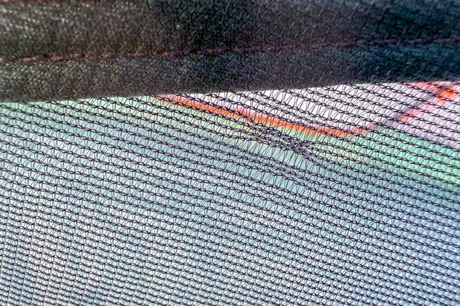 Close-up of the tent’s interior mesh fabric with visible stitching and the fly’s color faintly showing through.