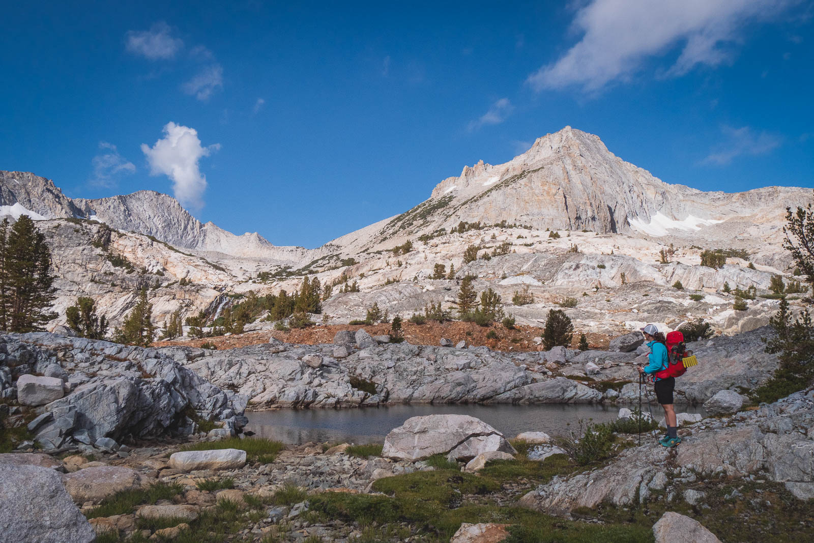 Pregnant person backpacking, surrounded by granite, enjoying the view.