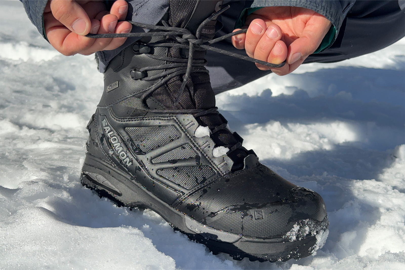 A close of of some hands tying the laces of the Toundra boots. There is snow in the background.