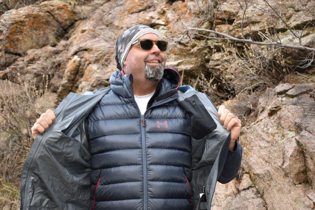 A male hiker shows the HIMALI Down Jacket layered underneath his rain jacket on a test hike