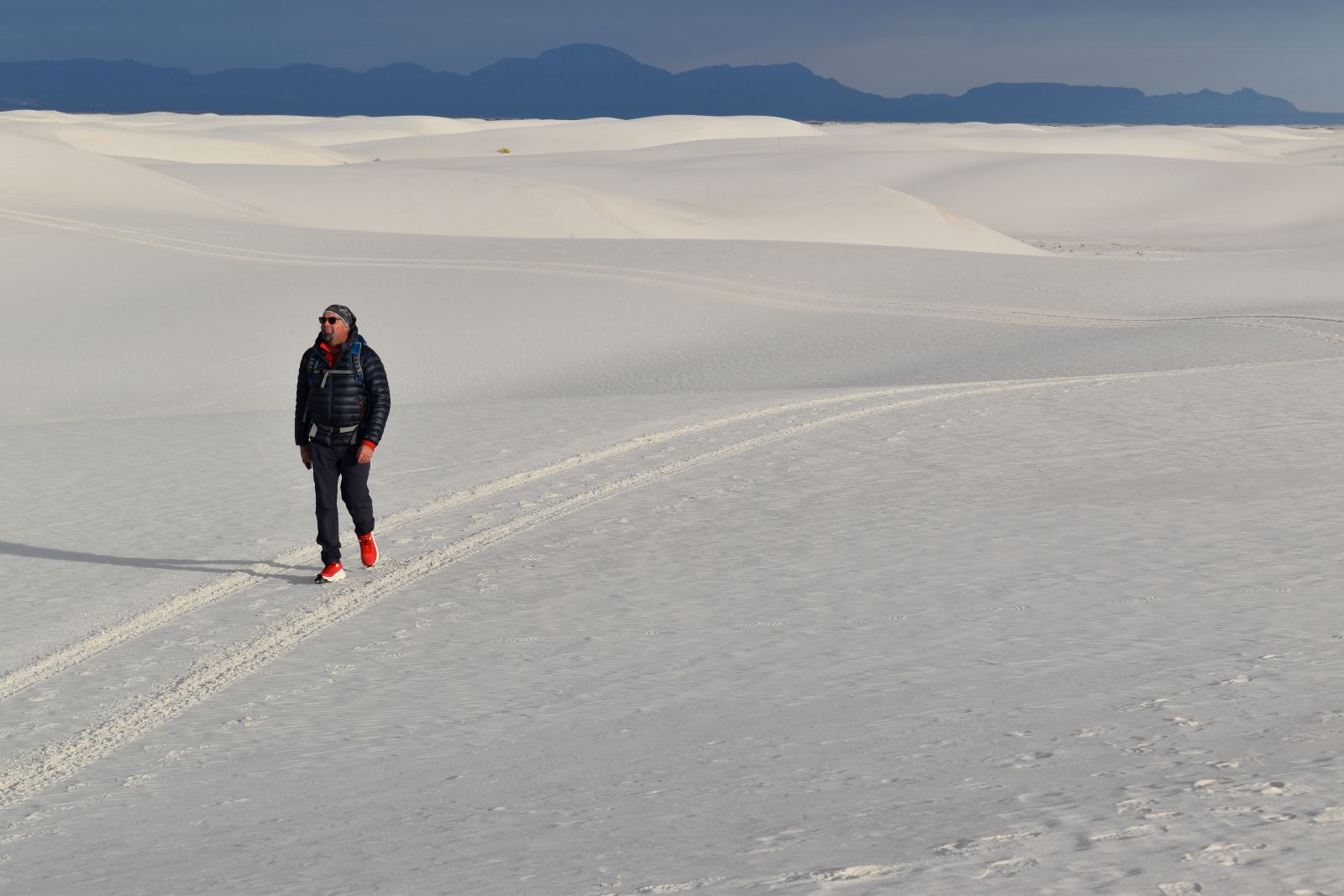 A hiker wears a blue Himali Down Jacket while hiking White Sands National Park