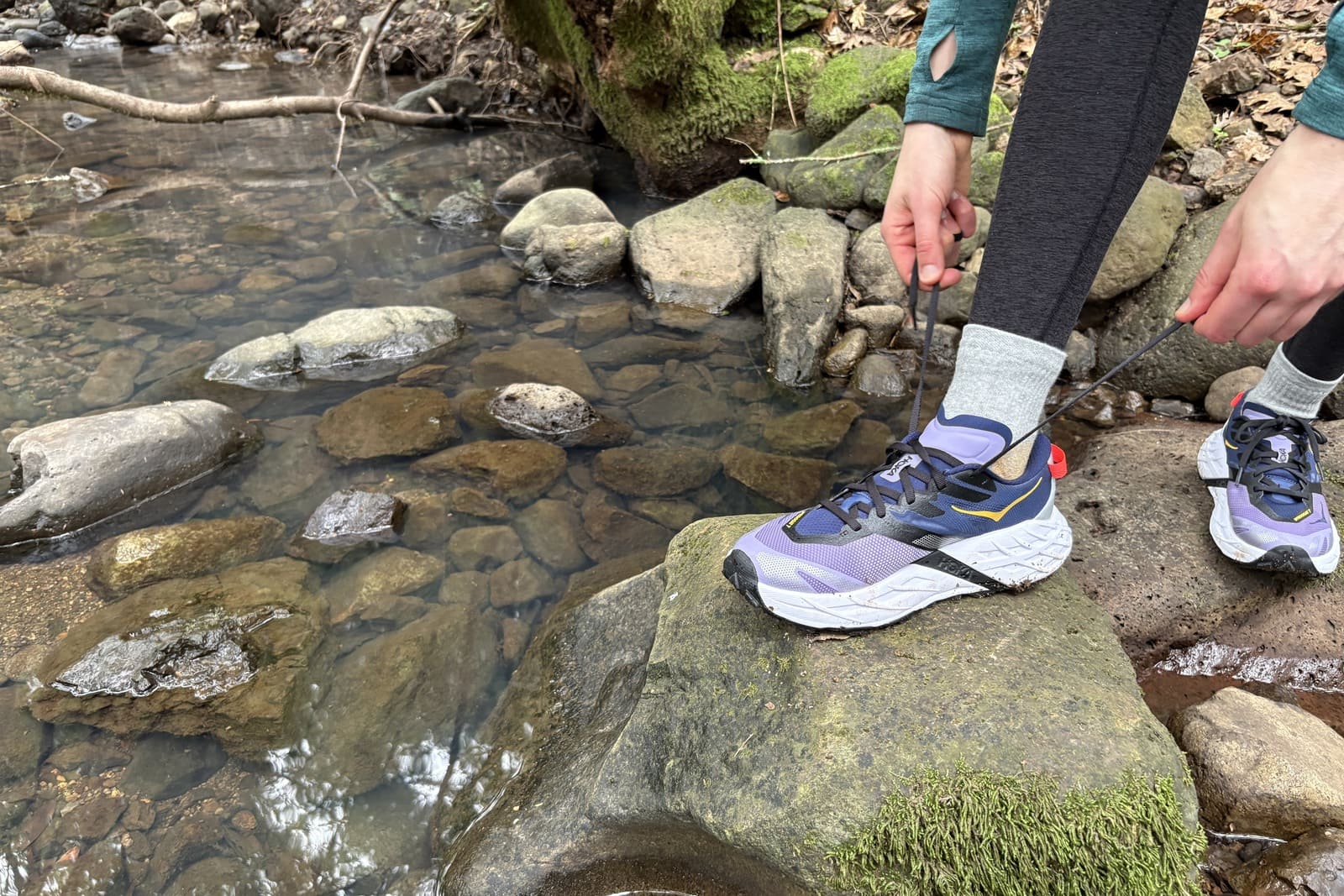A woman gets ready to tie her shoelaces on her trail runners.