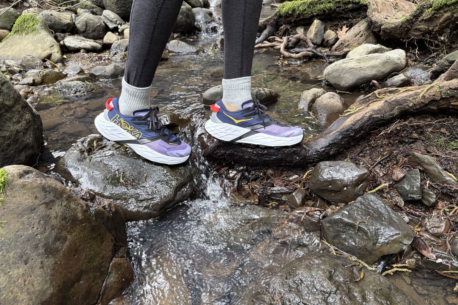 A woman crosses a small creek.