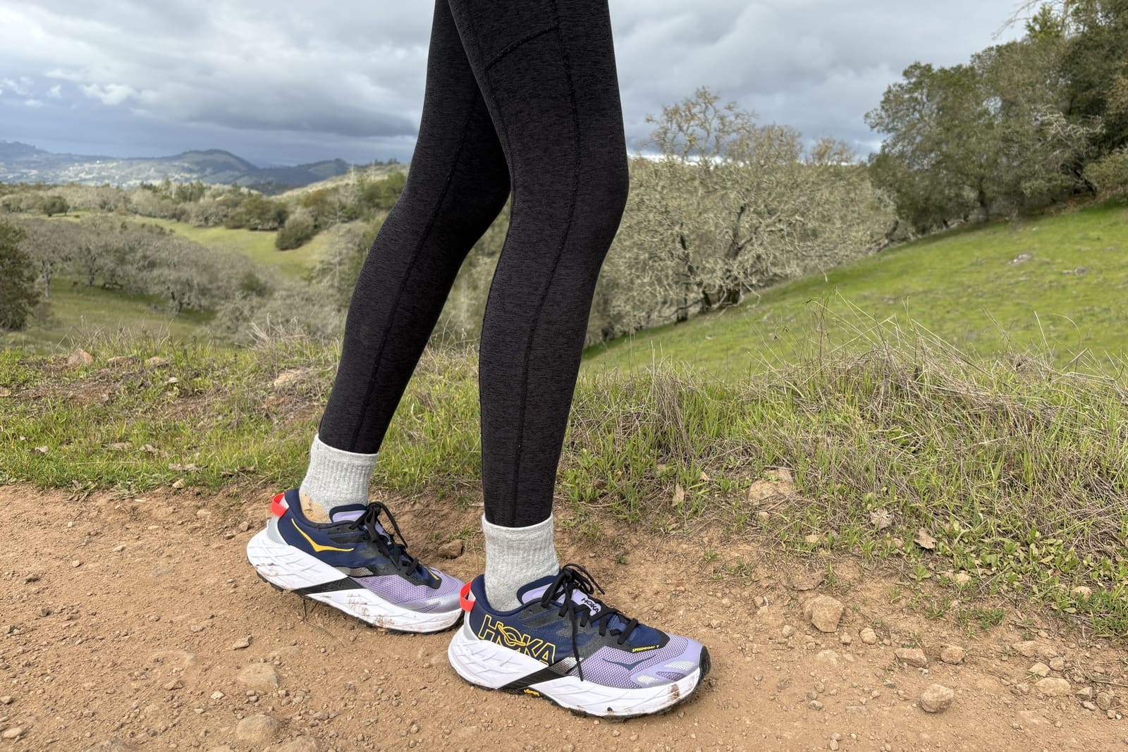 Closeup of a woman’s trail runners with a scenic backdrop.
