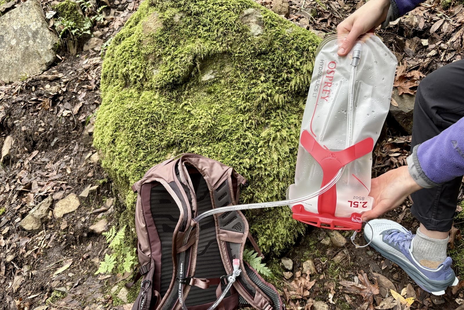 A woman shakes her hydration bladder upside down.