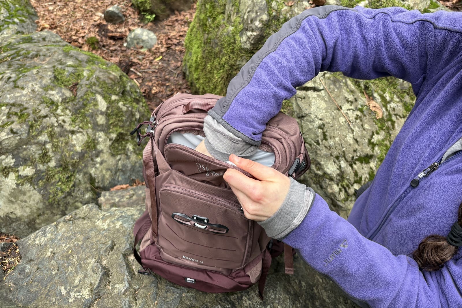 A woman reaches into her daypack.