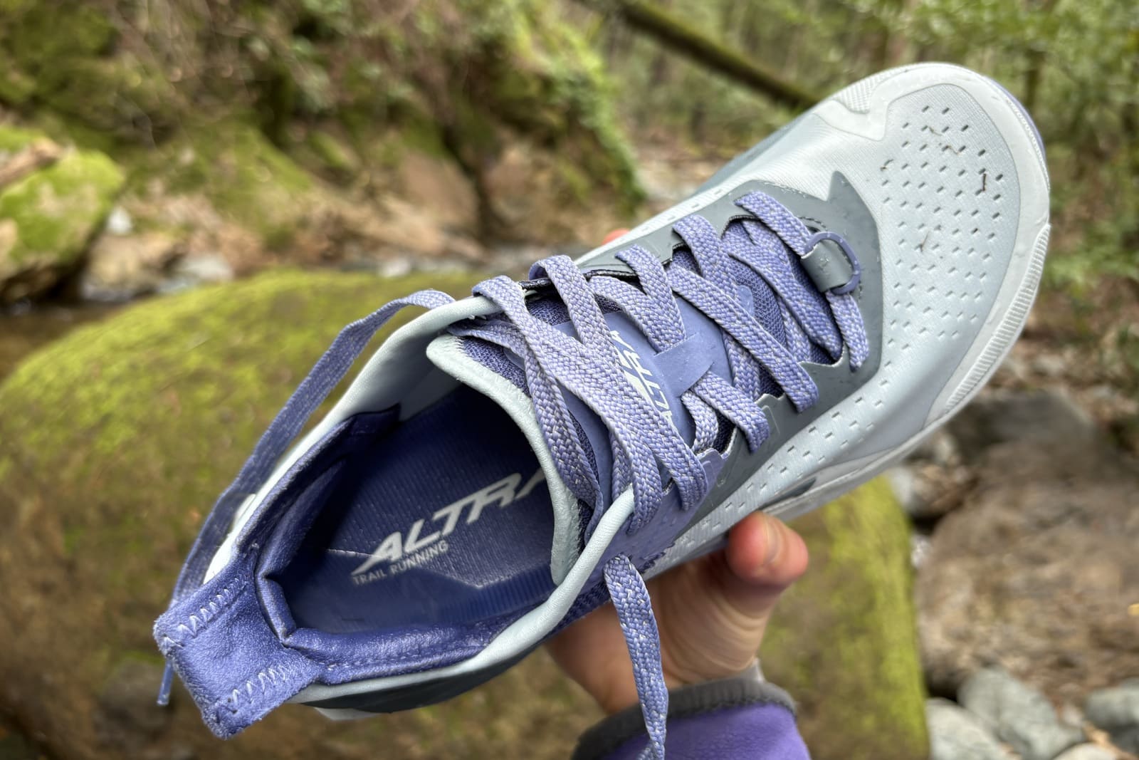 A woman holding up a shoe with water pooling inside the heel.