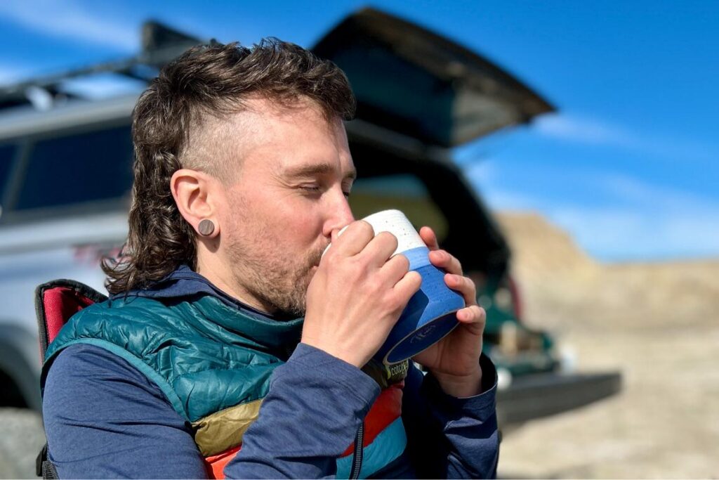 Up-close image of a man sipping coffee out of a mug with his eyes closed