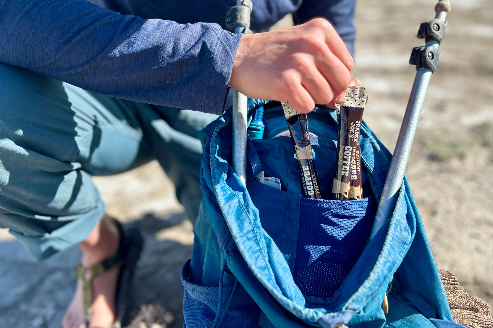 Up-close image of a person removing packets of Trader Joe's instant coffee from a daypack