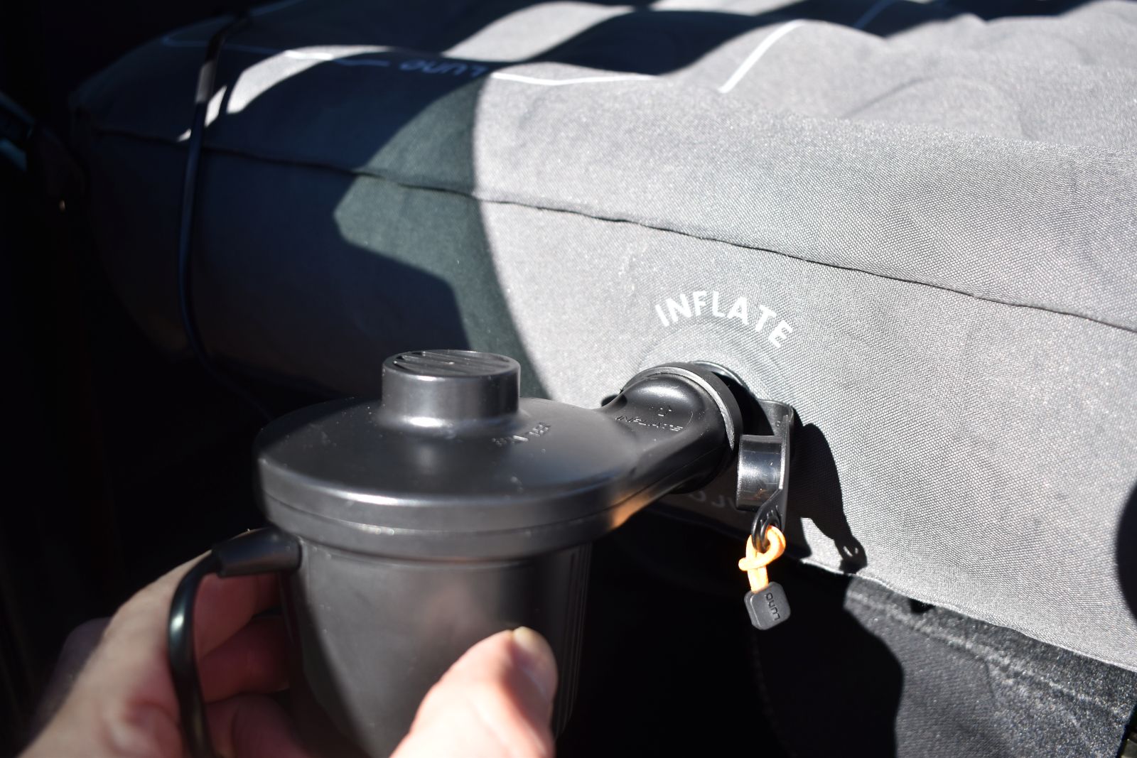 A camper inserts an air pump into the inflate valve of the Luno AIR Pro Vehicle Mattress.