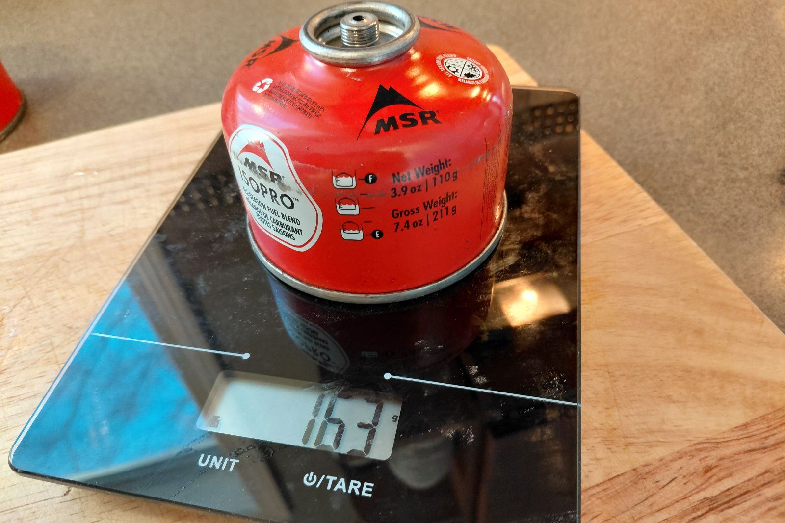 A camping fuel canister sits on an electronic scale.