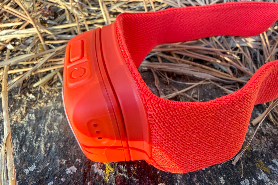 Angled view of the red BioLite headlamp and elastic strap on a rock, highlighting the compact design.