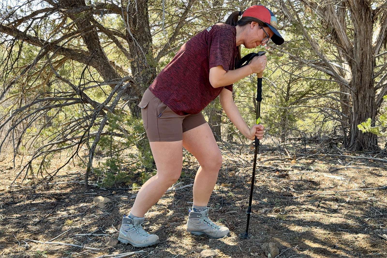 A person is leaning on the cascade poles with some pinion and juniper trees in the background.